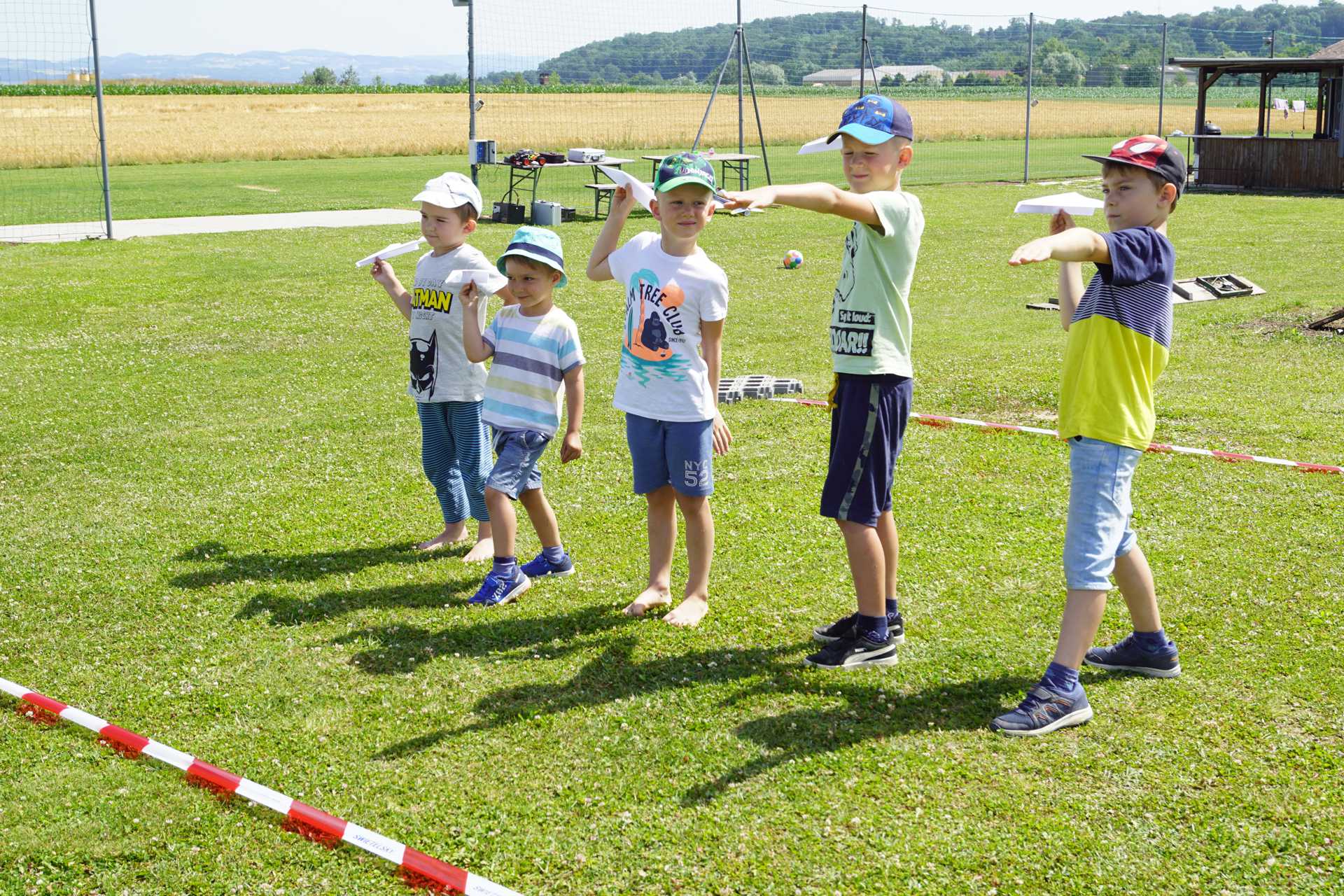 Foto: 5 Kinder mit selbst gebastelten Papierflugzeugen beim Weitwurf (vergrößerte Ansicht)