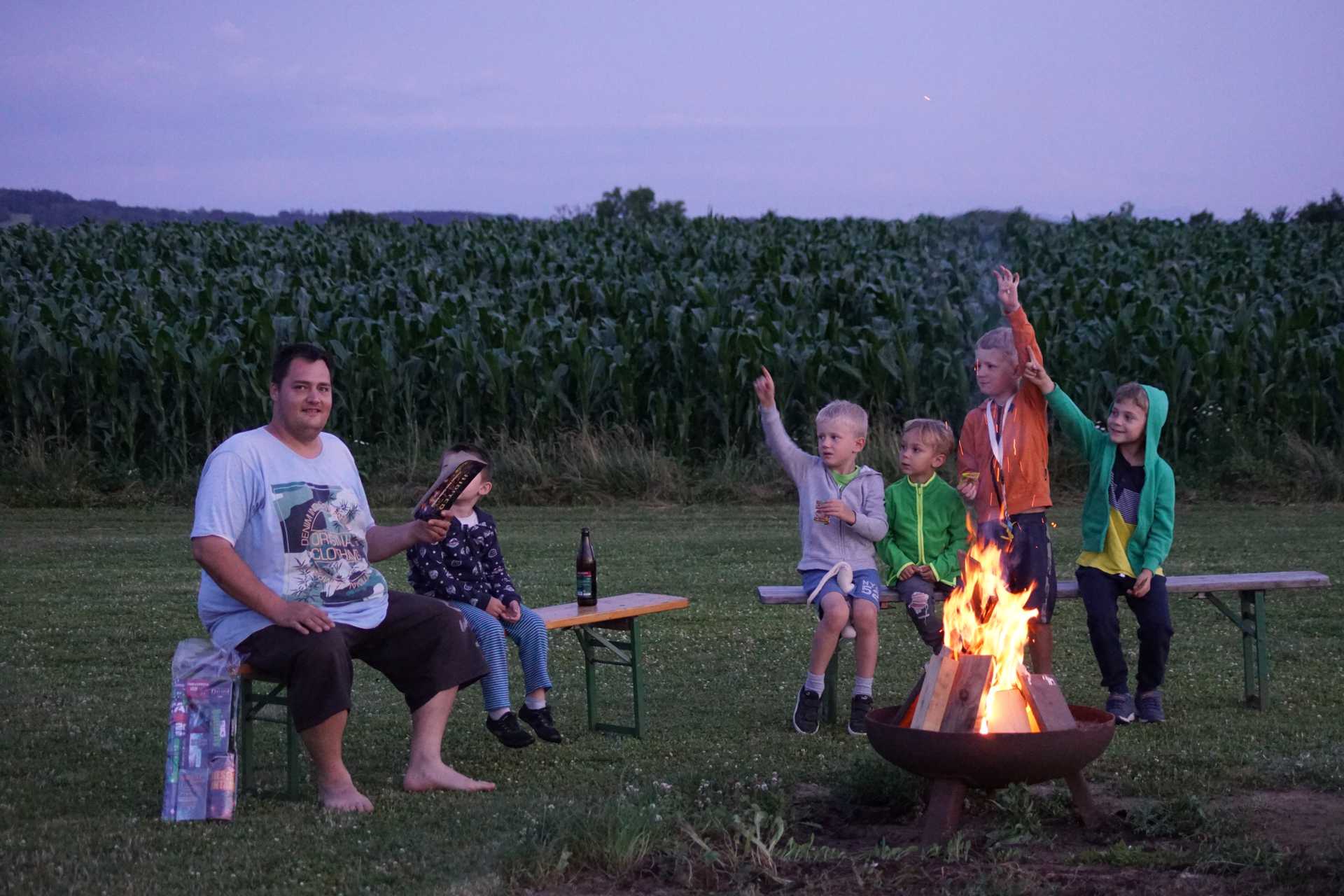 Foto: Kinder sitzen beim Lagerfeuer und braten Marshmallows (vergrößerte Ansicht)